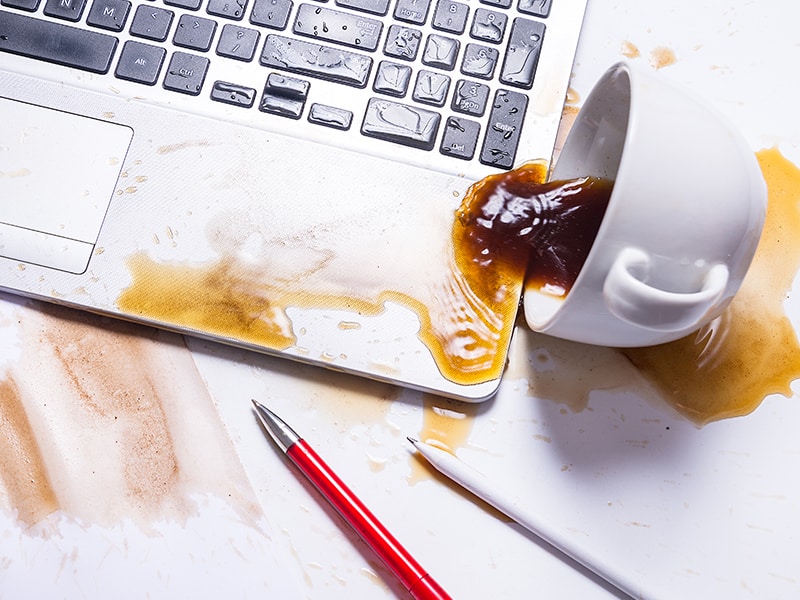 a cup of coffee that has been spilled onto a laptop