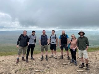 Some Atlas Cloud colleagues standing on a mountain peak