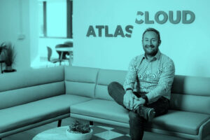 Man sat on sofa in front of Atlas Cloud logo